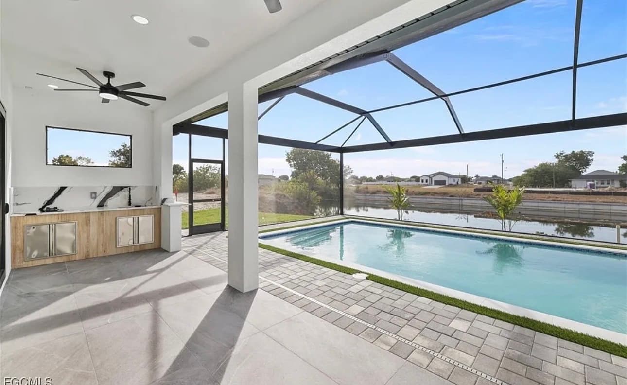Screened lanai with outdoor kitchen overlooking a private pool and canal